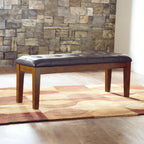 Signature Design by Ashley Ralene Tufted Upholstered Dining Room Bench, Medium Brown | Plush wipe-clean faux leather cushion, Frame of veneers, wood and engineered wood, Versatile 2-person entryway seating